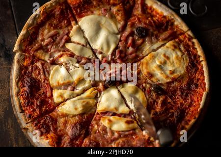 Frisch gekochte Pizza. Draufsicht. In Stücke geschnitten. Dunkler Hintergrund. Nahaufnahme. Stockfoto