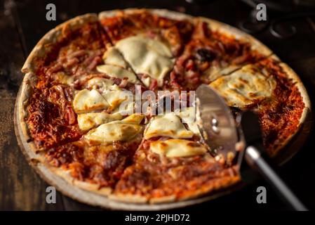 Frisch gekochte Pizza. In Stücke geschnitten. Dunkler Hintergrund. Nahaufnahme. Stockfoto