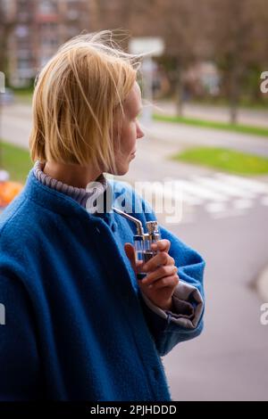 Marihuana rauchen. Eine Frau hält eine Mini-Bong. Entspannung im Freien. Cannabis ist legal. Stockfoto