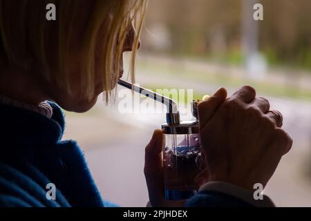 Eine Frau raucht Marihuana, Cannabis. Eine Erwachsene Frau mit blonden Haaren zündet ein Rauchergerät an. Entspannung, ärztliche Verschreibung. Stockfoto