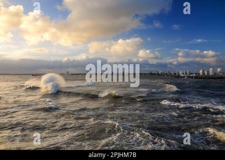 Blick auf die Bucht von Maldonado, mit den Gebäuden am Horizont, unter einem wolkigen Himmel und einem rauen Meer Stockfoto