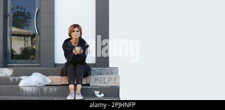 Arme Frau mit einem Becher, der bettelt und um Hilfe bittet, auf der Straße der Stadt, Platz für Text. Bannerdesign Stockfoto