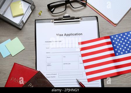 Visumantrag, amerikanische Flagge, Pässe und Schreibwaren auf Holztisch, flach liegend Stockfoto