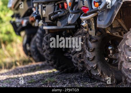 Nahaufnahme des Geländes von Quad Bike auf unbefestigten Landstraßen. Verschmutztes Rad eines Geländefahrzeugs mit Allradantrieb. Reise- und Abenteuerkonzept. Stockfoto