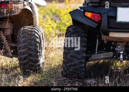 Nahaufnahme des Geländes von Quad Bike auf unbefestigten Landstraßen. Verschmutztes Rad eines Geländefahrzeugs mit Allradantrieb. Reise- und Abenteuerkonzept. Stockfoto