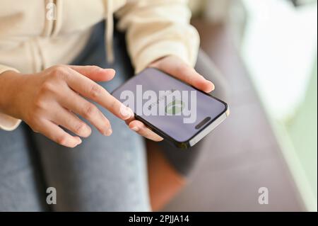 Chiang Mai, Thailand - März 31 2023: Eine Frau in Freizeitkleidung, die ihre WhatsApp-Anwendung auf ihrem Smartphone verwendet. IPhone mit WhatsApp-Logo auf dem Bildschirm Stockfoto