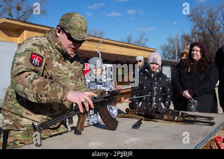 Ein territorialer Verteidigungskämpfer demonstriert während einer Übung für Zivilisten, die mit einer russischen Invasion der Ukraine an einem städtischen Strand in Kiew droht, einen Angriff der AK-47 abzubauen. Stockfoto