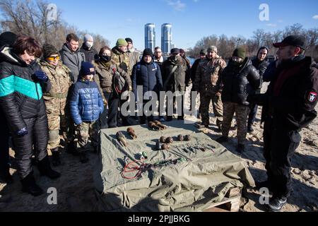 Ein territorialer Verteidigungskämpfer demonstriert während einer Übung für Zivilisten Handgranaten, die inmitten der Bedrohung durch eine russische Invasion der Ukraine an einem städtischen Strand in Kiew trainiert werden. Stockfoto