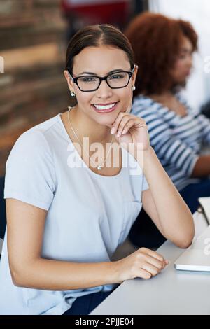 Sie nimmt ihren Erfolg in Schach. Porträt einer attraktiven jungen Frau, die in einem Büro sitzt. Stockfoto