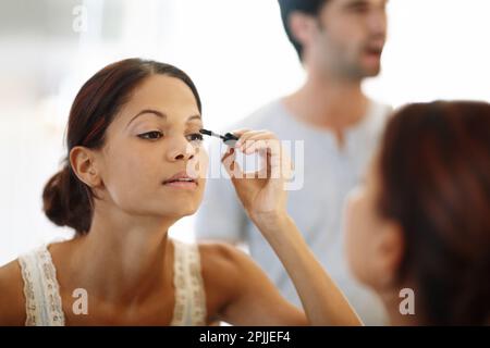Ich bereite mich auf den Tag vor. Eine attraktive junge Frau, die morgens ihre Mascara anlegt. Stockfoto