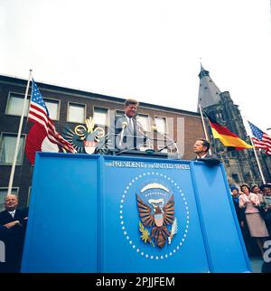 KN-C29238A 23. Juni 1963 Besuch von Präsident John F. Kennedy in Köln. Präsident Kennedy steht auf einem Rednerpodest, an dessen Seite der Dolmetscher Robert H. Lochner steht. Eunice Shriver und andere sehen sich die Rede des Präsidenten an. Rathaus, Köln, Deutschland. Bitte schreiben Sie Robert Knudsen. Fotos Vom Weißen Haus. John F. Kennedy Presidential Library and Museum, Boston“ Stockfoto