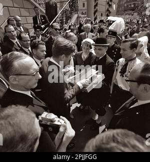 KN-C29294 23. Juni 1963 Präsident John F. Kennedy erhält ein Geschenk, nachdem er während seiner Reise nach Deutschland das Goldene Buch von Köln unterzeichnet hat. Auf dem Foto sehen Sie: Präsident Kennedy, Fotograf im Weißen Haus Cecil Stoughton (hoch oben auf der Treppe), Dolmetscher Robert H. Lochner, Beamte der Stadt und Zuschauer. Rathaus, Bonn, Deutschland. Bitte schreiben Sie Robert Knudsen. Fotos Vom Weißen Haus. John F. Kennedy Presidential Library and Museum, Boston“ Stockfoto