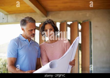 Stellen Sie sicher, dass Sie Platz für einen Pool lassen. Ein Mann und eine Frau, die Blaupausen machen. Stockfoto