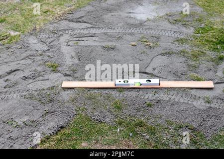 Verwenden Sie eine Wasserwaage zum Bewegen und Planieren von Boden im Rasen Stockfoto