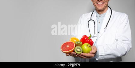 Ernährungswissenschaftler mit frischen Produkten auf hellgrauem Hintergrund, Nahaufnahme mit Platz für Text. Bannerdesign Stockfoto