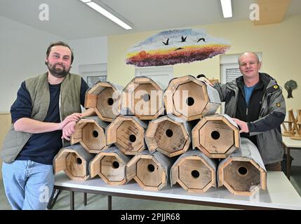 23. März 2023, Brandenburg, Luckau: Philipp Juranek (l), Amateur-Ornithologe und Naturschützer, und Ralf Donat, Direktor des Wanninchen Nature Experience Center der Sielmann Foundation, stehen neben Hufeisenzuchtkästen in einem Lagerhaus des Wanninchen Nature Experience Center. Vier Hobby-Ornithologen im Süden Brandenburgs beweisen, dass Bier die Wiedereinführung des Hufeisens fördern kann, was selten geworden ist: Mit dem Verkauf ihres "Hufeisens" finanzieren sie den Bau wetterbeständiger Nistkästen. Und der Vogel ist offensichtlich glücklich darüber. Foto: Patrick Pleul/dpa Stockfoto