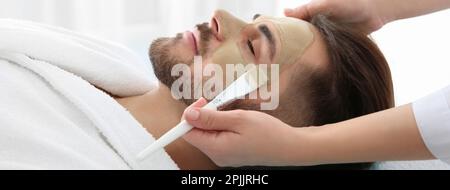 Kosmetologe, der eine Maske auf das Gesicht des Klienten aufträgt, im Spa-Salon. Bannerdesign Stockfoto
