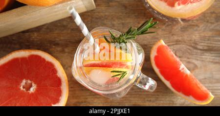 Flache Liegezusammensetzung mit Maurerglas aus aufgepumptem Wasser und Grapefruitscheiben auf einem Holztisch. Bannerdesign Stockfoto