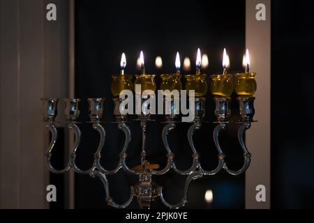 Hanukka-Kerzen werden in einer silbernen Lampe angezündet. Kerzen gefüllt mit Olivenöl Stockfoto