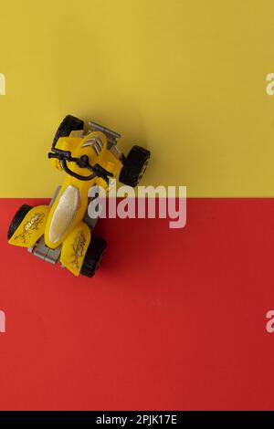 Miniatur-ATV in Gelb auf gelbem und rotem Hintergrund Stockfoto