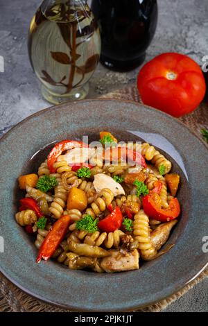 Pasta mit gebratenem Hähnchen, Pilzen, Pfeffer und Kürbis Stockfoto