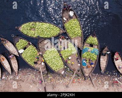 3. April 2023, Dhaka, Dhaka, Bangladesch: Dutzende von Booten, die Tausende von leuchtend grünen Wassermelonen transportieren, legen an einem geschäftigen Markt in der Nähe des Buriganga in Dhaka, Bangladesch an. Händler bringen die Früchte - bis zu 2 00.000 pro Tag - aus ländlichen landwirtschaftlichen Flussgebieten in die Hauptstadt Dhaka, um sie landesweit zu verteilen. Die Arbeiter, die nur 3,50 GBP pro Tag verdienen, verbringen den ganzen Tag damit, schwere Körbe mit Wassermelonen zu entladen. Jede Wassermelone wird für weniger als 1 GBP verkauft. Wassermelone ist in tropischen Ländern wie Bangladesch sehr gefragt und erleichtert jedem die Wärme. Voll von h Stockfoto