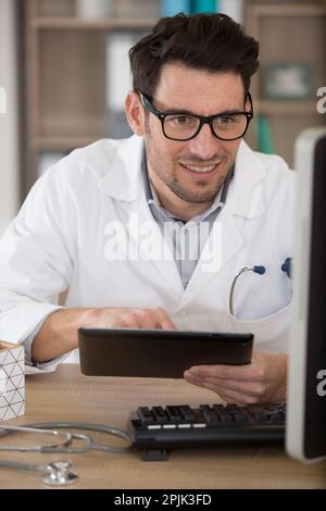 Attraktiver Arzt in der Praxis mit einem digitalen Tablet Stockfoto
