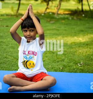 Asiatisch kluges Kind, das Yoga macht, im Gesellschaftspark draußen, Kinder Yoga Pose. Der kleine Junge, der Yoga macht Stockfoto