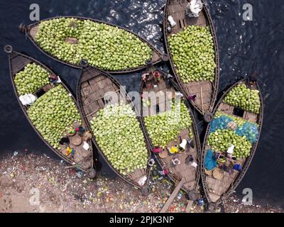 3. April 2023, Dhaka, Dhaka, Bangladesch: Dutzende von Booten, die Tausende von leuchtend grünen Wassermelonen transportieren, legen an einem geschäftigen Markt in der Nähe des Buriganga in Dhaka, Bangladesch an. Händler bringen die Früchte - bis zu 2 00.000 pro Tag - aus ländlichen landwirtschaftlichen Flussgebieten in die Hauptstadt Dhaka, um sie landesweit zu verteilen. Die Arbeiter, die nur 3,50 GBP pro Tag verdienen, verbringen den ganzen Tag damit, schwere Körbe mit Wassermelonen zu entladen. Jede Wassermelone wird für weniger als 1 GBP verkauft. Wassermelone ist in tropischen Ländern wie Bangladesch sehr gefragt und erleichtert jedem die Wärme. Voll von h Stockfoto