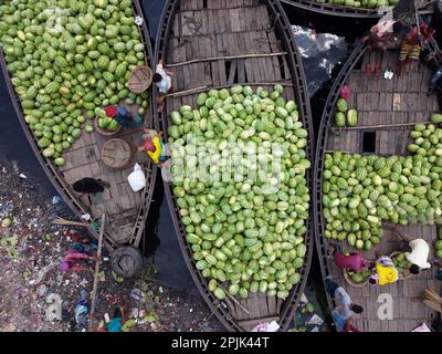 3. April 2023, Dhaka, Dhaka, Bangladesch: Dutzende von Booten, die Tausende von leuchtend grünen Wassermelonen transportieren, legen an einem geschäftigen Markt in der Nähe des Buriganga in Dhaka, Bangladesch an. Händler bringen die Früchte - bis zu 2 00.000 pro Tag - aus ländlichen landwirtschaftlichen Flussgebieten in die Hauptstadt Dhaka, um sie landesweit zu verteilen. Die Arbeiter, die nur 3,50 GBP pro Tag verdienen, verbringen den ganzen Tag damit, schwere Körbe mit Wassermelonen zu entladen. Jede Wassermelone wird für weniger als 1 GBP verkauft. Wassermelone ist in tropischen Ländern wie Bangladesch sehr gefragt und erleichtert jedem die Wärme. Voll von h Stockfoto