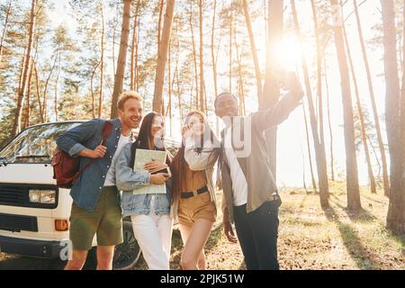 Selfie machen. Eine Gruppe junger Menschen reist tagsüber zusammen im Wald Stockfoto