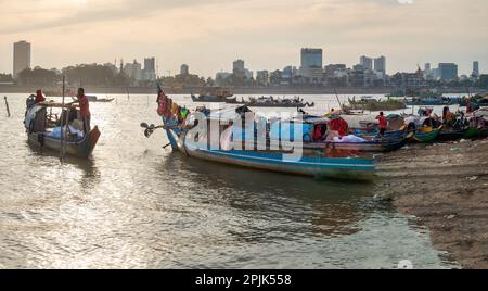 Phnom Penh, Kambodscha-Dezember 24. 2022: Kleine, schmale Boote, teilweise gegen die Elemente bedeckt und von Khmer-Familien als Unterkünfte genutzt, sitzen auf weniger Stockfoto