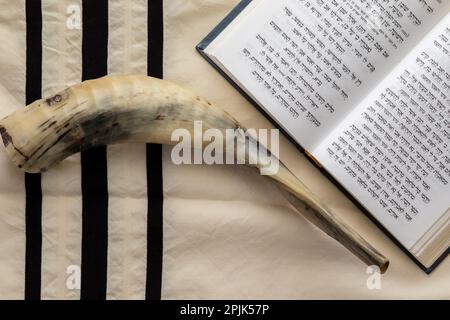 07-07-2022. jerusalem-israel. Ein Gebetsbuch für den jüdischen Rosch-Hashana-Feiertag - offen und auf einem Talllit neben einem Schofar aus einem Lammhorn platziert Stockfoto