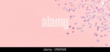 Banner mit winzigen silbernen Kristallkonfetti auf pinkfarbenem Pastellhintergrund. Selektiver Fokus. Platz für Text. Stockfoto