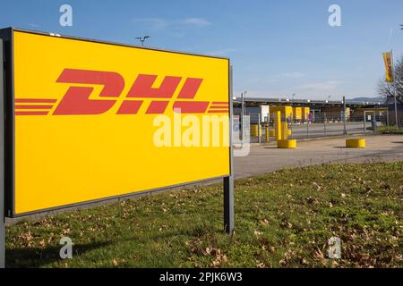 Koblenz, Deutschland - 20. Februar 2023: Firmenaufkleber „DHL“ am Eingang des lokalen Vertriebszentrums mit Lkw vor dem Logistikzentrum Stockfoto