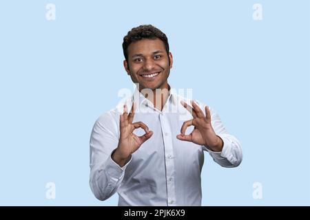 Der Indianer zeigt das Zeichen mit beiden Händen. Isoliert auf pastellblauem Hintergrund. Stockfoto