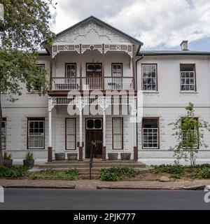 Stadtbild mit kunstvoller Portiko in einem traditionellen, malerischen Haus an der Straße, aufgenommen in hellem bewölktem Sommerlicht, Stellenbosch, Westkap, Südafrika Stockfoto