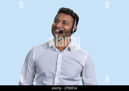 Porträt eines jungen lächelnden indianers mit Headset. Geschäftsmann oder Kundendienstmitarbeiter. Isoliert auf blau. Stockfoto