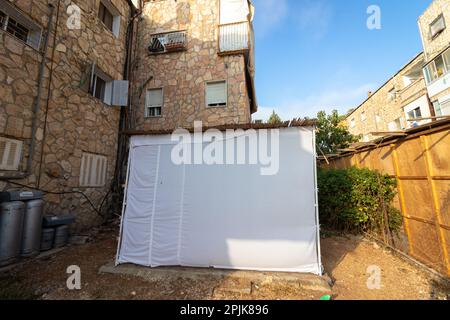 Sukkah bedeckt mit weißem Stoff, erbaut im Hof eines Gebäudes in Jerusalem. Der jüdische Feiertag von Sukkot Stockfoto