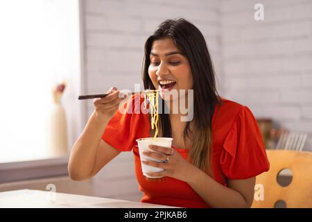 Porträt einer Frau, die Nudeln in der Küche isst Stockfoto