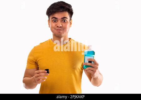 Junger Mann spült den Mund mit Mundwasser aus Stockfoto