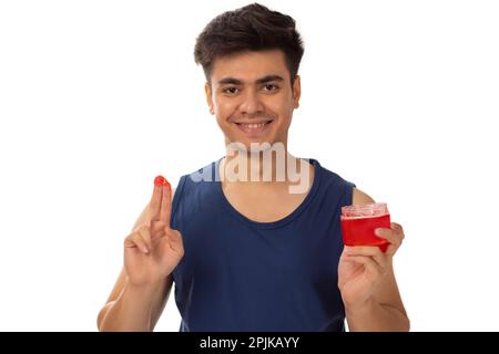 Porträt eines jungen Mannes, der Haargel vor weißem Hintergrund aufträgt Stockfoto