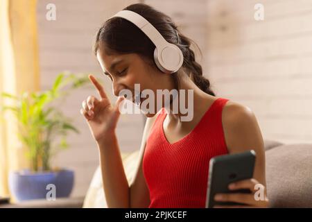 Nahaufnahme eines fröhlichen Mädchens, das Musik über Kopfhörer hört Stockfoto