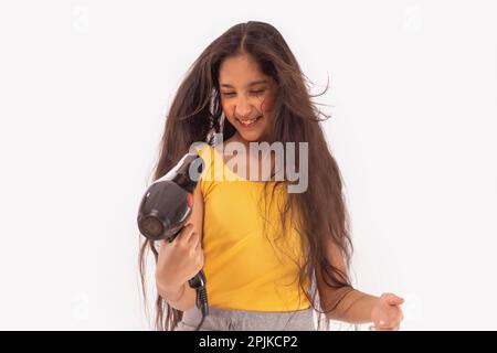 Ein Mädchen trocknet sich die Haare vor weißem Hintergrund Stockfoto