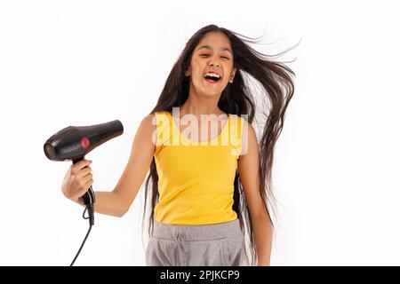 Ein Mädchen trocknet sich die Haare vor weißem Hintergrund Stockfoto