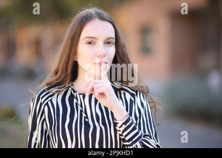 Eine elegante Frau, die auf der Straße um Ruhe bittet und vor die Kamera schaut Stockfoto