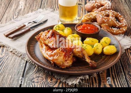 Gegrilltes Hähnchen mit gekochten Kartoffeln und Tomatensauce, serviert mit Bier und Brezeln auf dem Holztisch. Horizontal Stockfoto