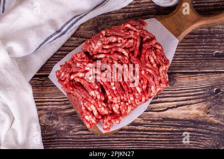 Hackfleisch auf Holzhintergrund. Rohes Hackfleisch von Kühen oder Hackfleisch. Draufsicht Stockfoto