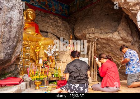 Laos, Luang Prabang. MwSt. Thammo Thayaram am Mount Phousi. Gläubige und Buddha-Statue. (Nur Redaktionelle Verwendung) Stockfoto