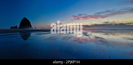 USA, Oregon. Cannon Beach und Panoramablick auf Hystack bei Sonnenuntergang und Ebbe. Stockfoto